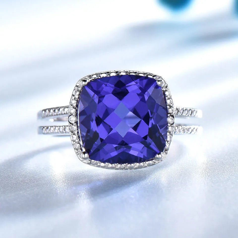 A sterling silver ring for women with a bright blue tanzanite stone, shown on a hand.