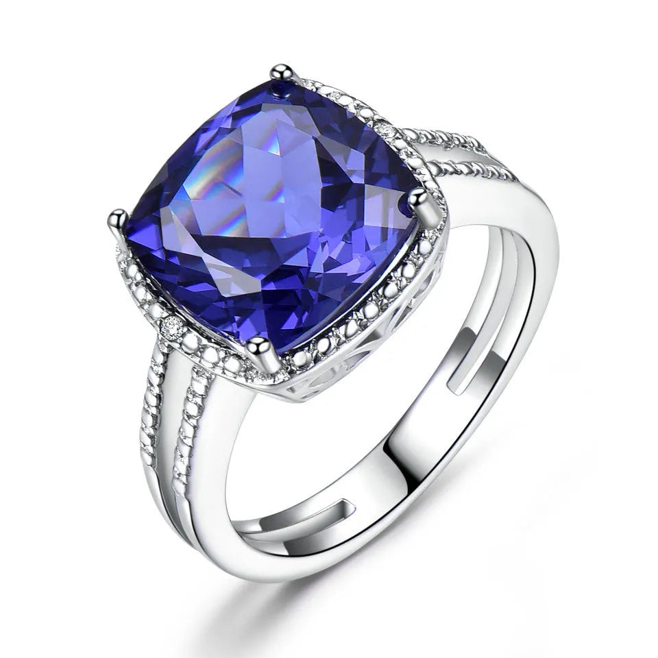 A sterling silver ring for women with a bright blue tanzanite stone, shown on a hand.