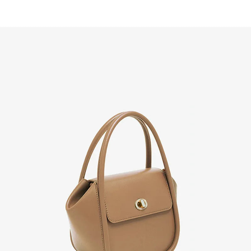 Brown leather wing-shaped tote bag with a buckle detail and latch closure, shown with a single cross-body strap.
