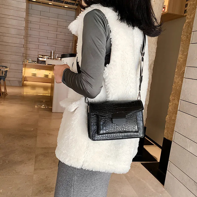 Vintage style black crossbody bag with an adjustable shoulder strap on a mannequin.