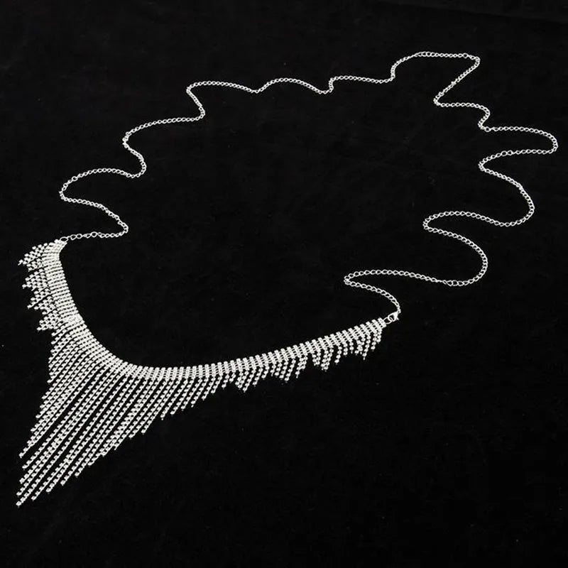 Silvery rhinestone body chain laid flat on a white surface showing metal links and clear stones