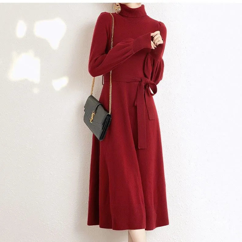 A woman wearing a rose red loose knitted turtleneck dress with a big hem midi skirt.