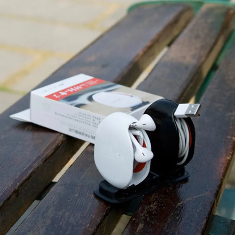 Automatic earphone cable winder retractor in blue, showing compact size next to a 3.5mm jack.
