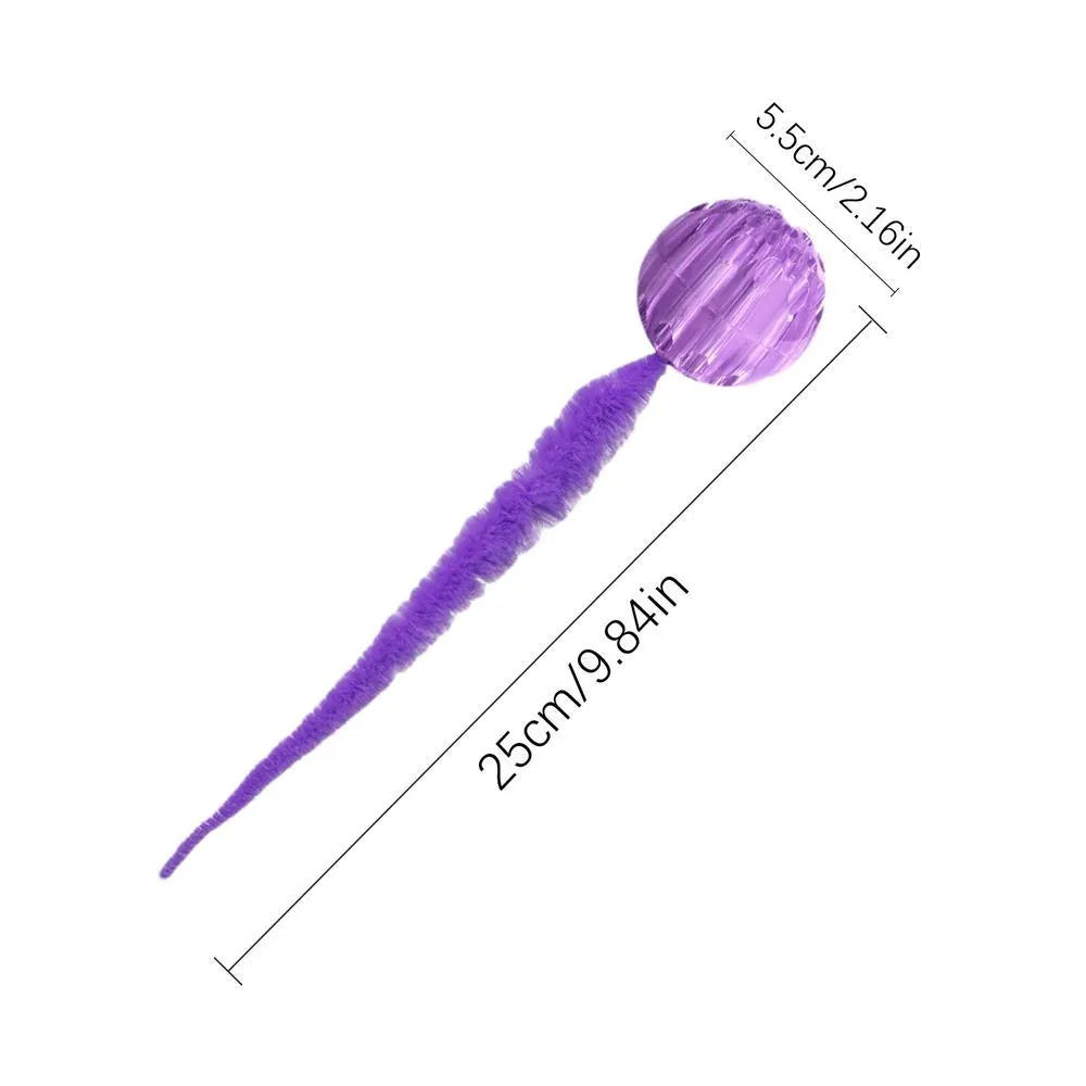 Green bouncy ball cat toy with plush tail on wooden floor
