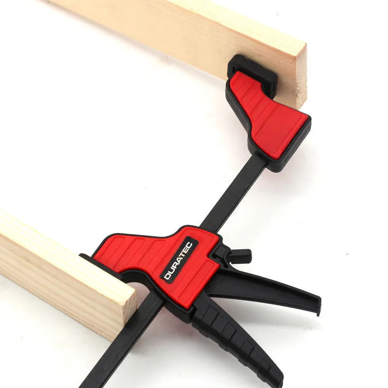 Black plastic woodworking clamp with quick release key and soft rubber grip pads