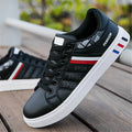 Men's black sports shoes on a white background, showing the classic trainer design and rubber sole.