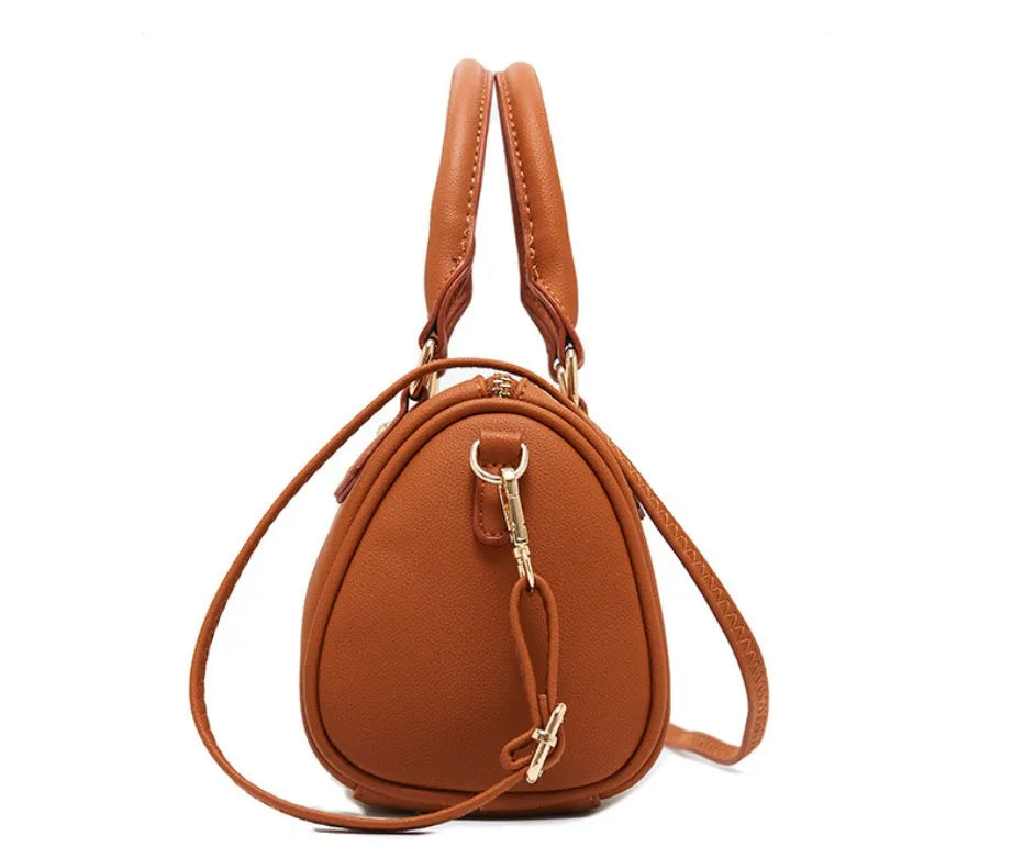 Ladies pillow crossbody bag in PU with zip closure and letter detail, shown in available colours.
