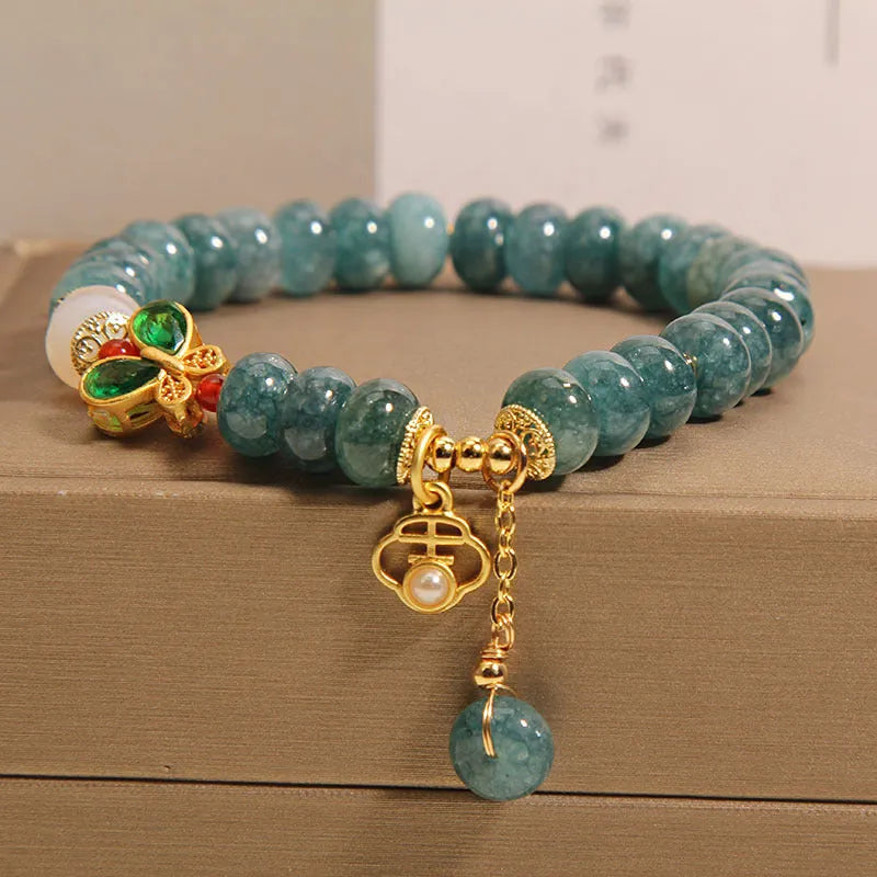 Blue water jade bead bracelet with white agate abacus beads and a butterfly charm.