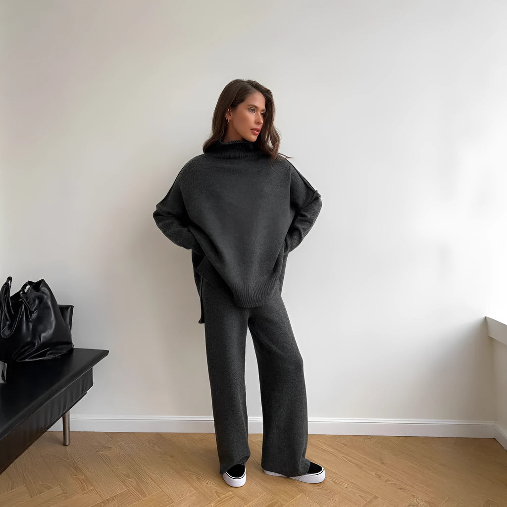 Women's dark grey acrylic knit set with side-slit top and full-length trousers laid flat.
