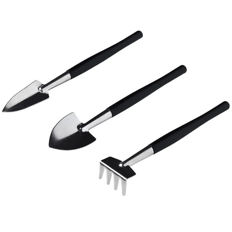 16-piece black mini garden tool set for succulents on a 75cm square cushion, showing shovel, tweezers, spray bottle, and brush.