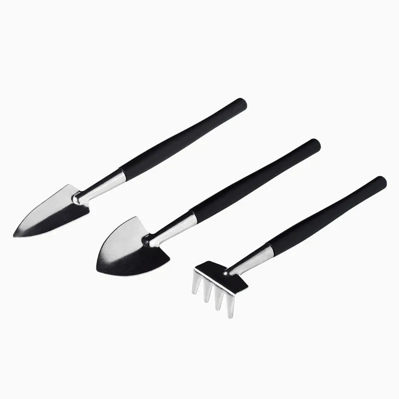 16-piece black mini garden tool set for succulents on a 75cm square cushion, showing shovel, tweezers, spray bottle, and brush.