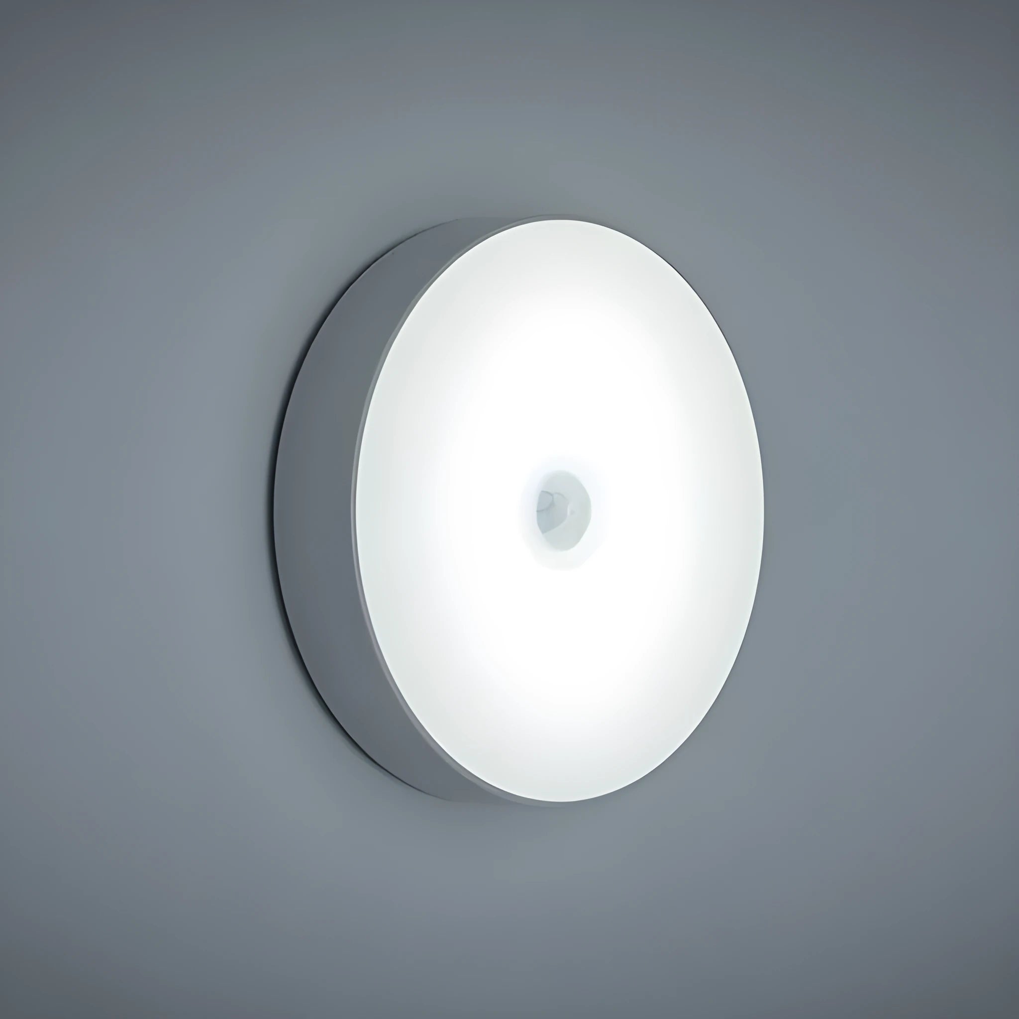 Small white circular motion sensing LED night light with USB charging cable and adhesive tape.