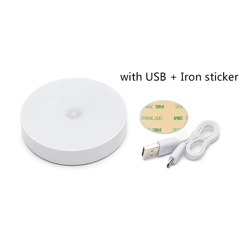 Small white circular motion sensing LED night light with USB charging cable and adhesive tape.