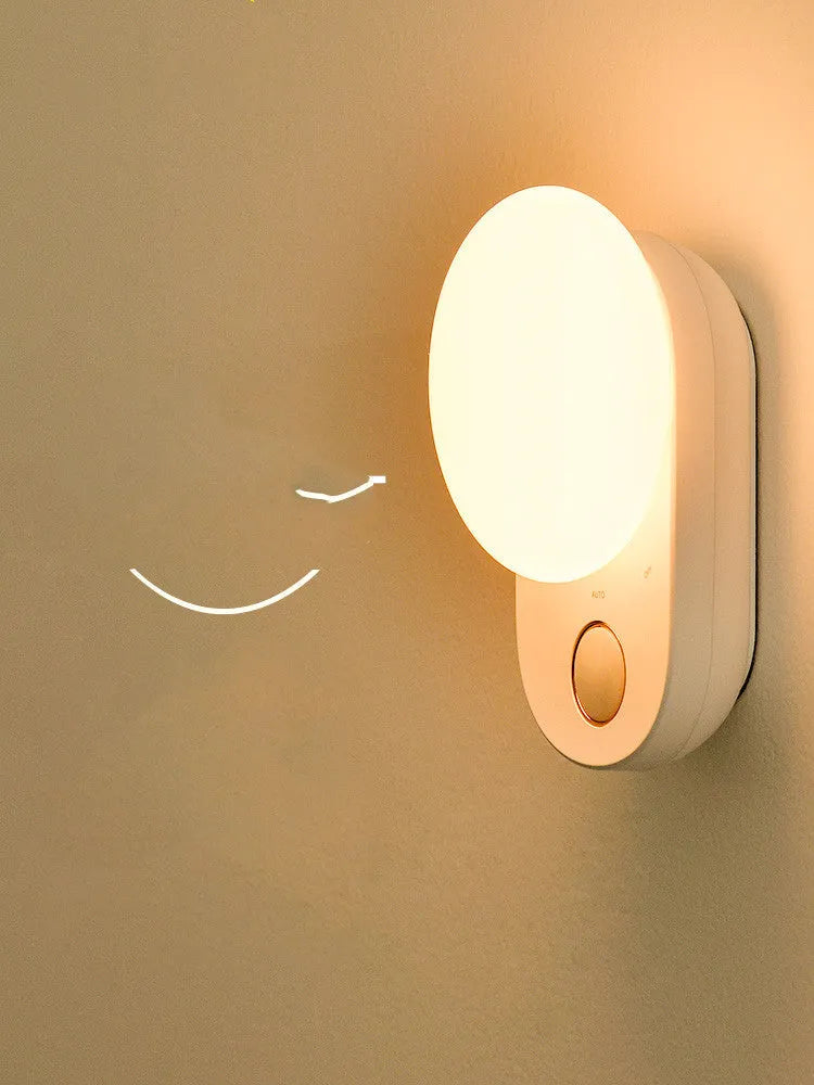 White Baseus rechargeable night light with motion sensor on a wooden bedside table.