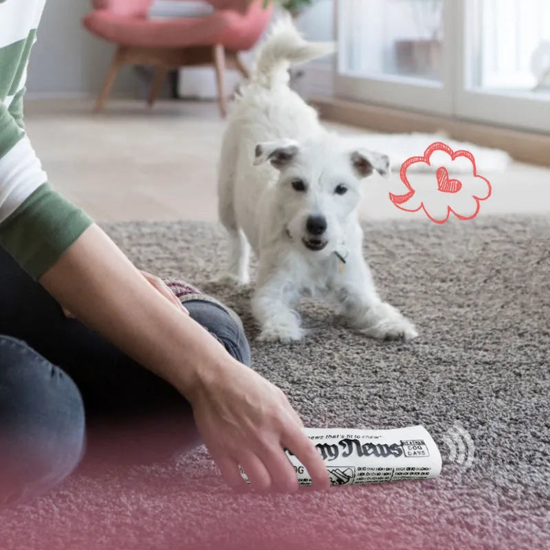 Squeaky black and white PVC dog toy shaped like a rolled newspaper on a surface