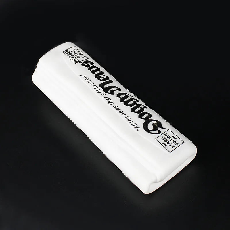 Squeaky black and white PVC dog toy shaped like a rolled newspaper on a surface