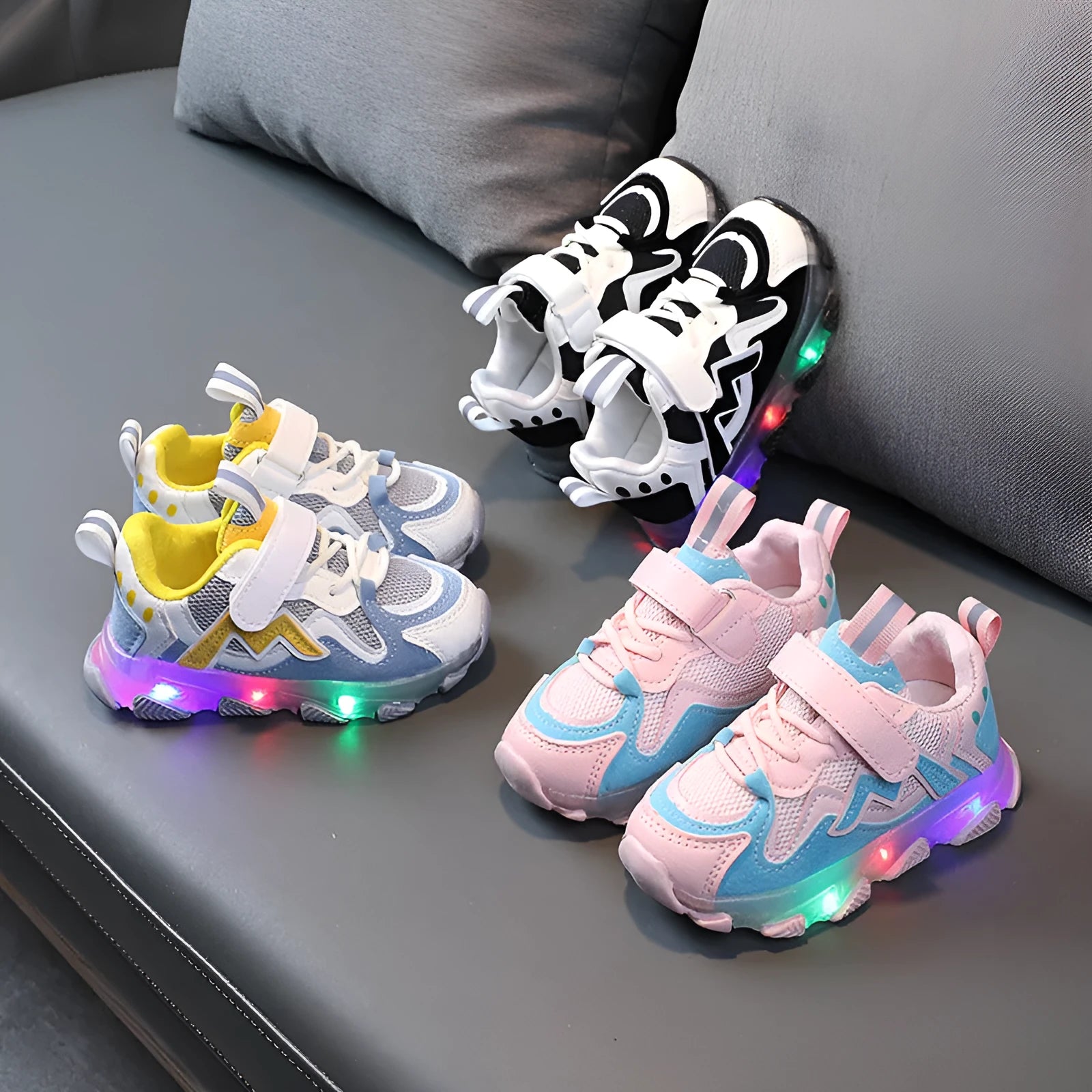 Kids' black light-up sneakers with mesh panels, Velcro strap, and glowing LED lights in the sole.
