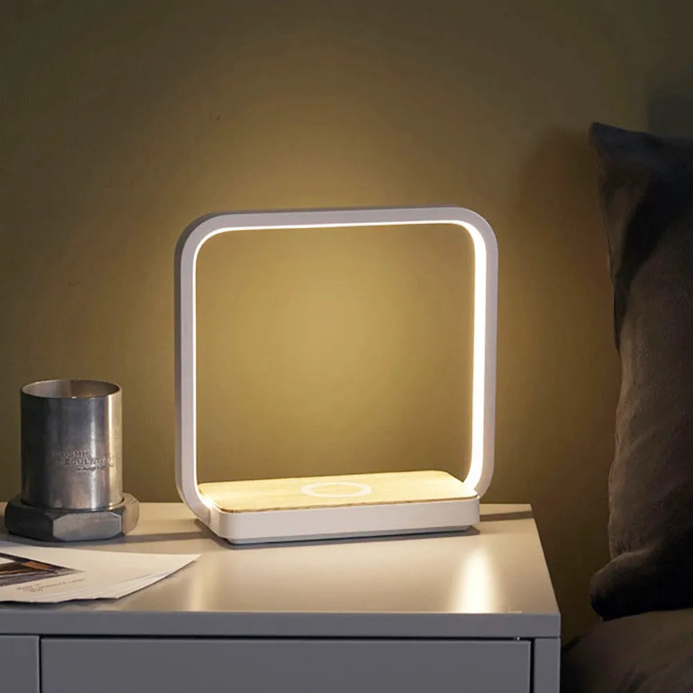 Modern white smart bedside lamp with touch base and USB cable on a wooden nightstand.
