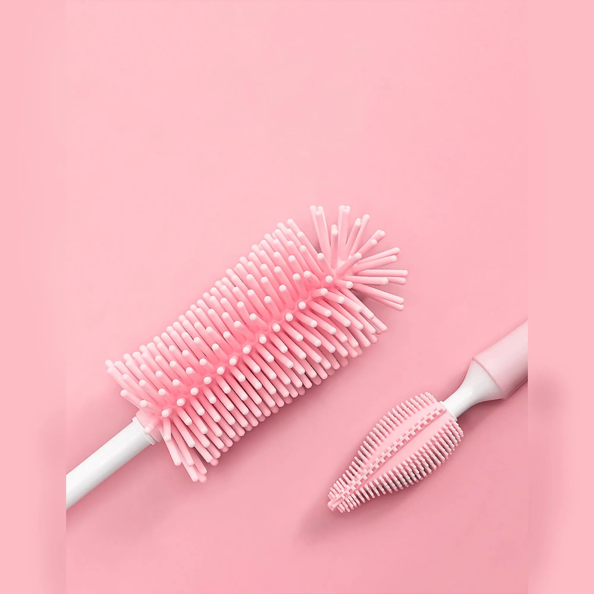 Three silicone baby bottle brushes in blue, pink, and yellow with straw scrubber on white background