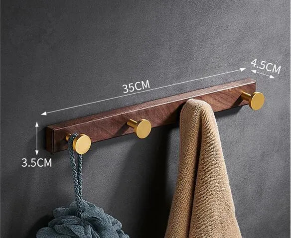 Black Walnut and brass-finished aluminium wall-mounted row hooks in a perforated style.