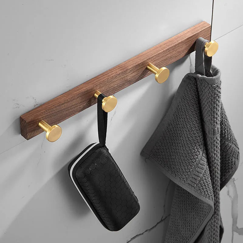 Black Walnut and brass-finished aluminium wall-mounted row hooks in a perforated style.