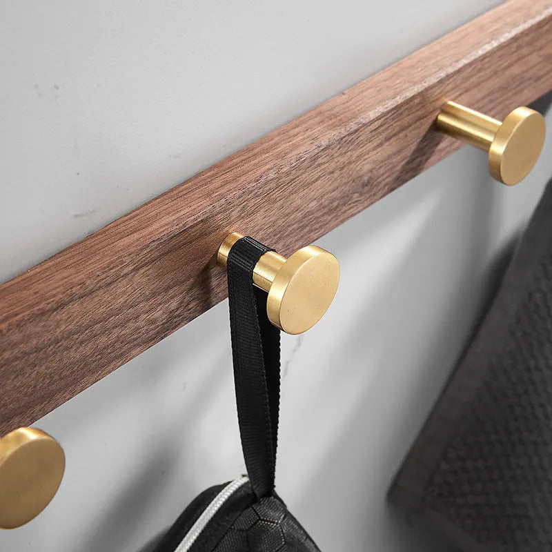 Black Walnut and brass-finished aluminium wall-mounted row hooks in a perforated style.