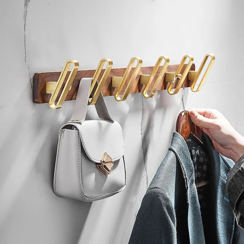 Black Walnut and brass-finished aluminium wall-mounted row hooks in a perforated style.