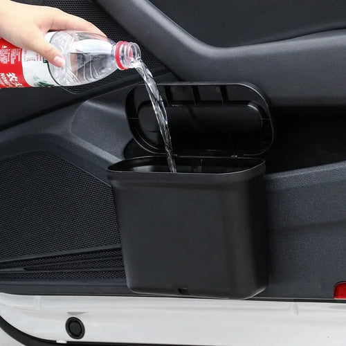 Black 1.7L PP plastic car trash can suspended on centre console with lid open, interior visible