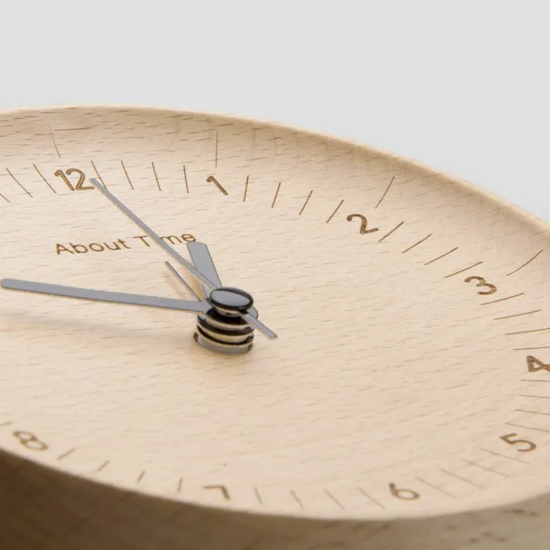AboutTime log mute pendulum alarm clock in German beech wood, 12cm diameter, featuring Sun brand movement, on a simple desk