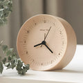 AboutTime log mute pendulum alarm clock in German beech wood, 12cm diameter, featuring Sun brand movement, on a simple desk