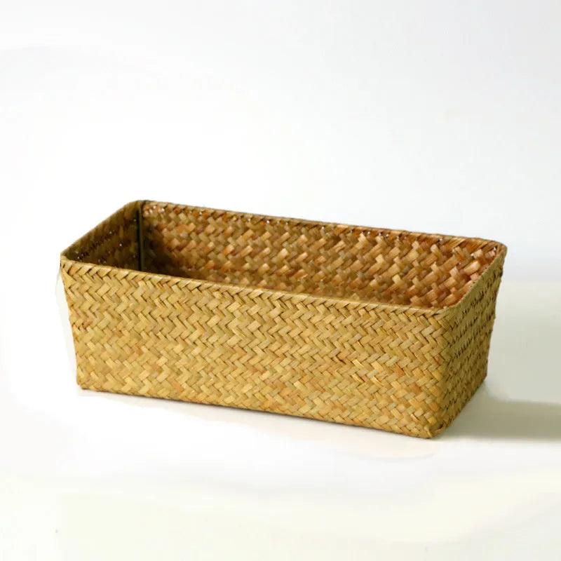 Natural brown woven straw desk storage box with a lid, shown on a wooden surface.