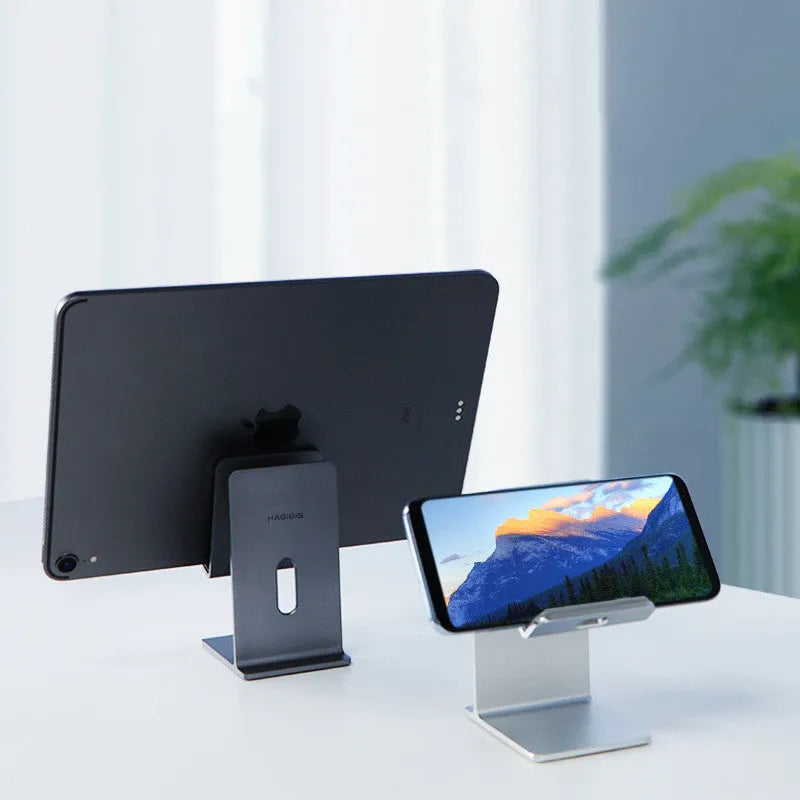 Dark Space Gray alloy mobile phone holder with adjustable arm holding a smartphone on a wooden desk.