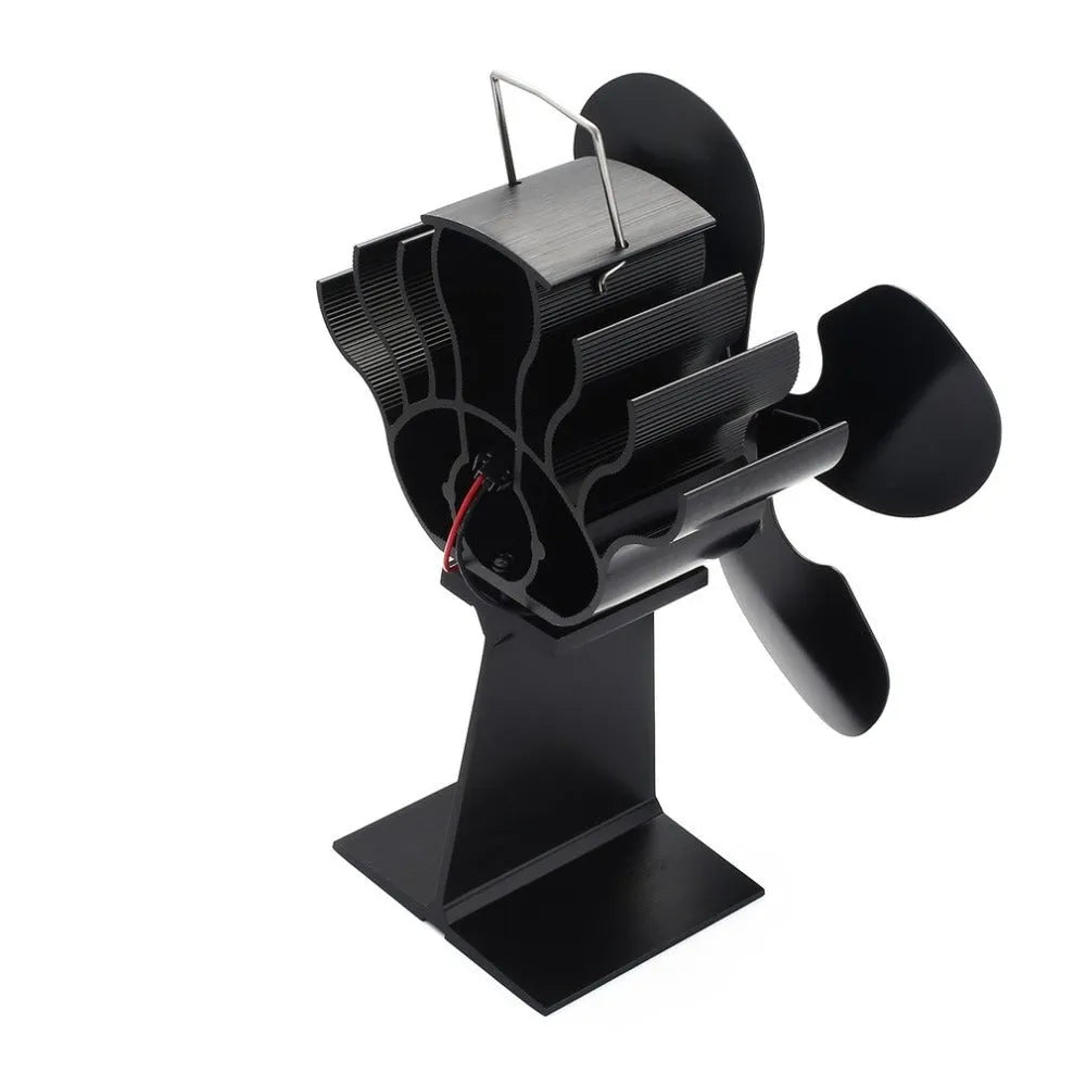 Black thermodynamic fireplace fan with Yotsuba style blades, placed on a fireplace surface
