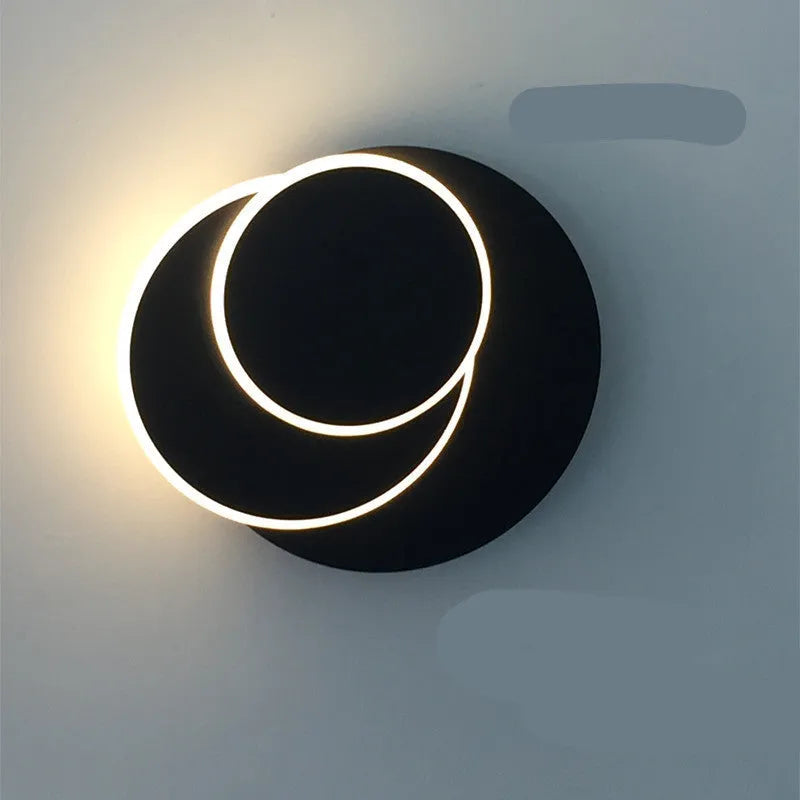 Modern round acrylic wall lamp in black or white, mounted on a wall with push-button switch.