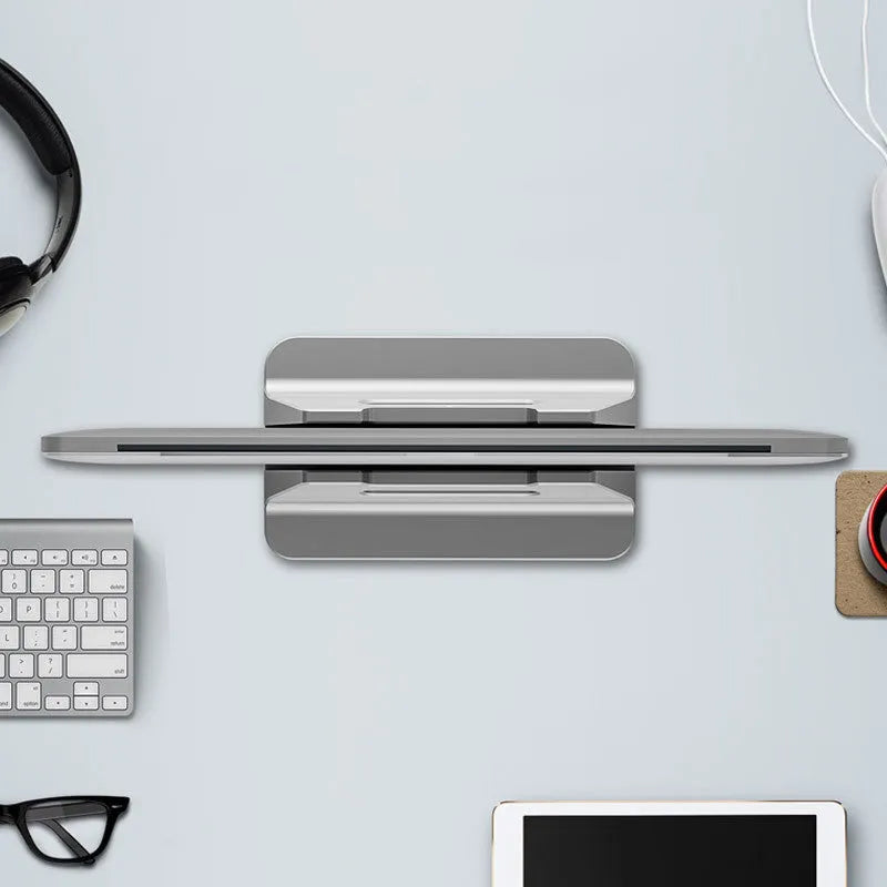 Silver aluminium alloy vertical notebook storage bracket on desk holding a laptop upright
