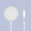Silver metallic MagSafe-compatible magnetic wireless charger for iPhone on a wooden desk.
