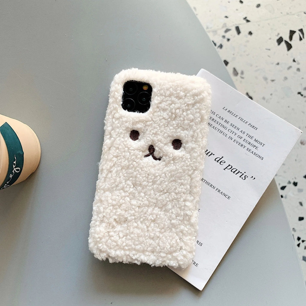 Brown embroidered plush cartoon bear face on a clear TPU iPhone 11 case, showing raised edges.