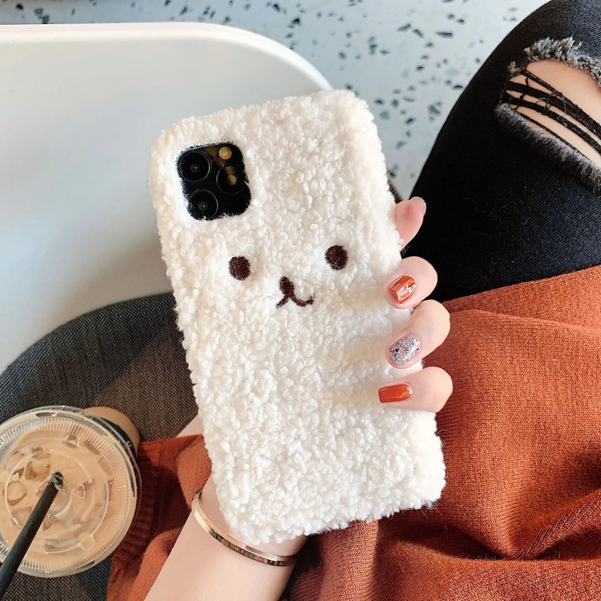 Brown embroidered plush cartoon bear face on a clear TPU iPhone 11 case, showing raised edges.