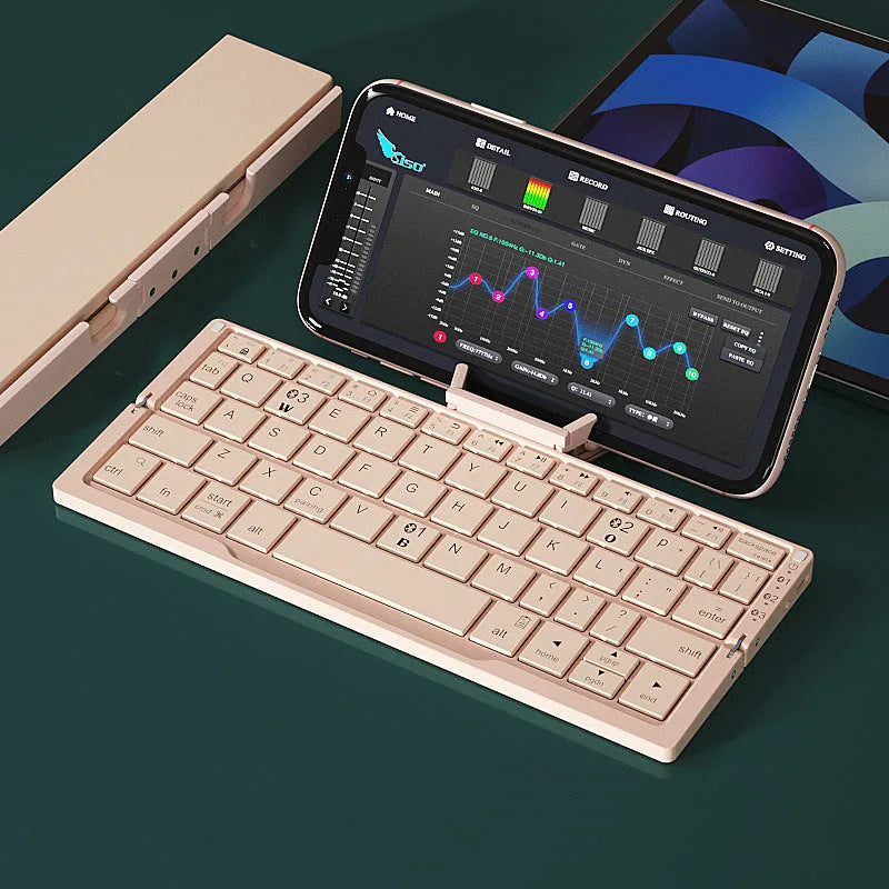 Silver white aluminium folding Bluetooth keyboard shown open next to a smartphone propped on its hidden stand.
