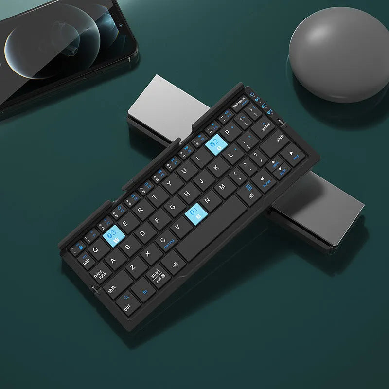 Silver white aluminium folding Bluetooth keyboard shown open next to a smartphone propped on its hidden stand.