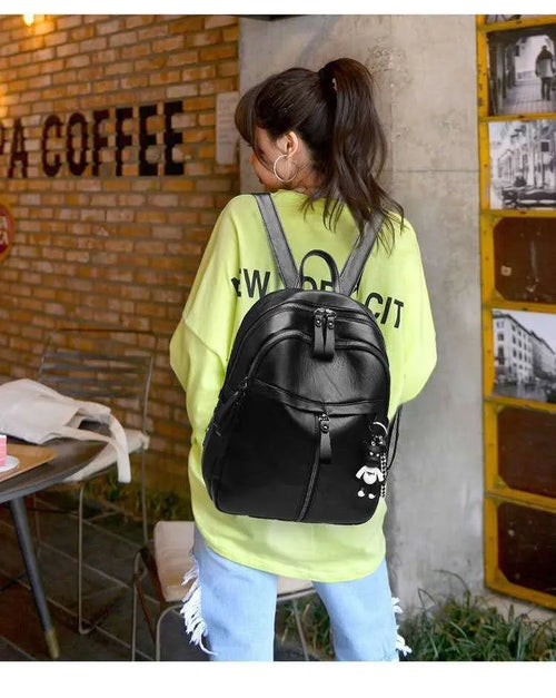 Black soft surface PU leather backpack showing medium size with shoulder straps and luggage strap attachment