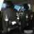 Black PU leather car seat back hanging organiser with storage pockets and a removable bin attached to a car headrest.