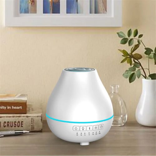Round white Bluetooth humidifier and essential oil diffuser with night light on a wooden surface.
