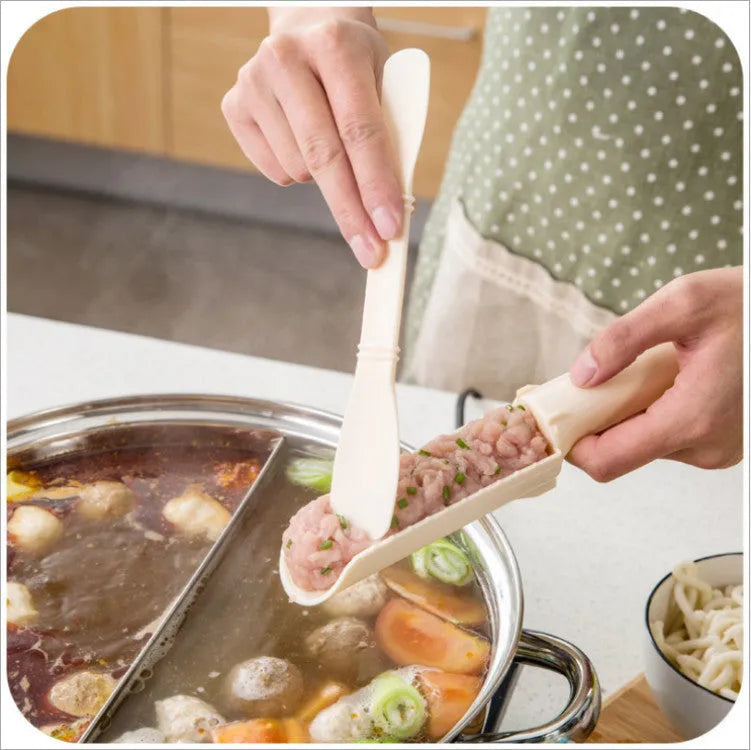 Stainless steel meatball maker with rounded scoop on a kitchen countertop