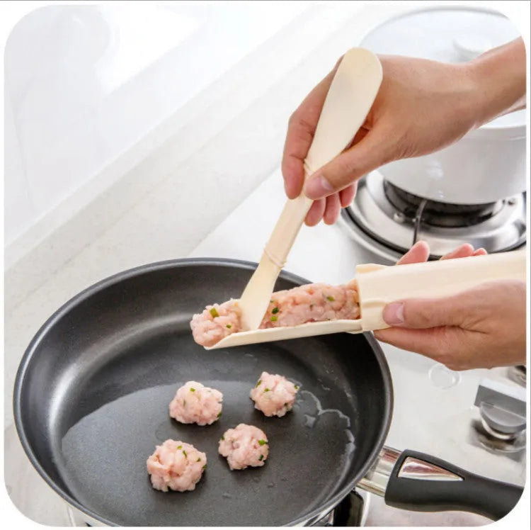 Stainless steel meatball maker with rounded scoop on a kitchen countertop