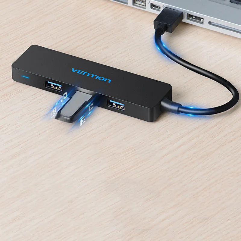 Black four-port USB 3.0 hub with a short cable, nickel-plated ports, and ABS plastic body on a desk
