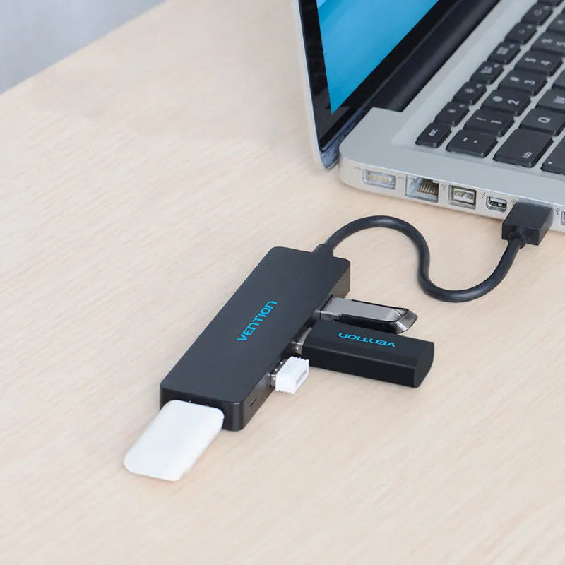 Black four-port USB 3.0 hub with a short cable, nickel-plated ports, and ABS plastic body on a desk