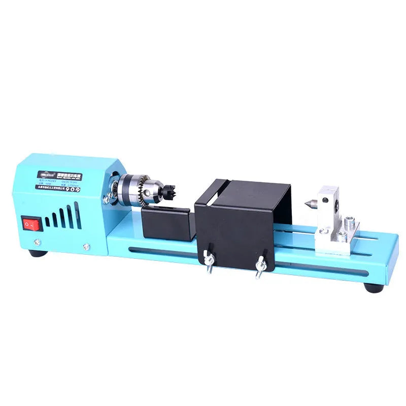 Mini woodworking lathe in blue with steel chuck, drill bit, and protective cover on a desktop