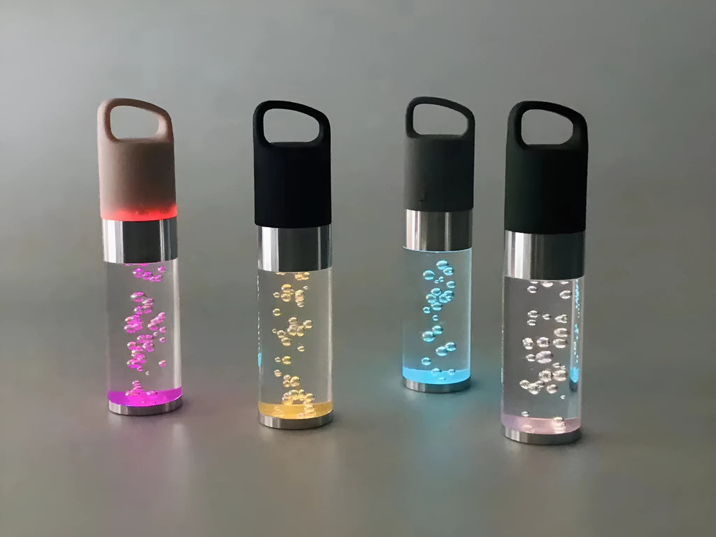 Compact colourful Bluetooth speaker with glowing crystal lights, shown in pink, black, silver grey, and green colour options.