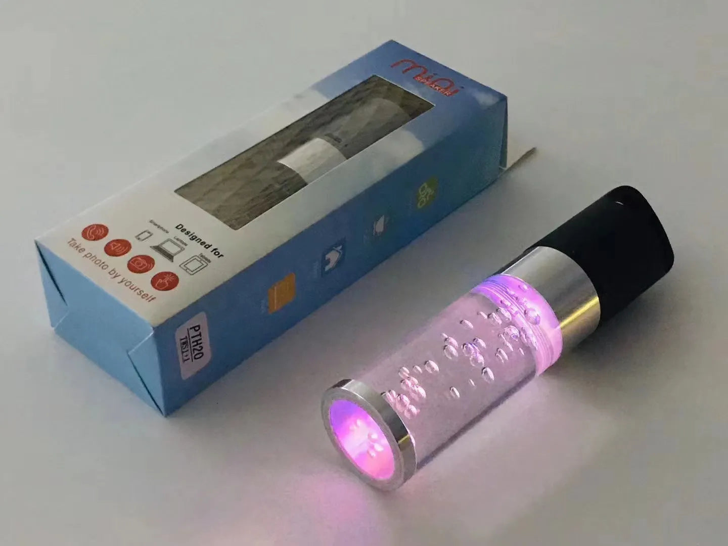 Compact colourful Bluetooth speaker with glowing crystal lights, shown in pink, black, silver grey, and green colour options.